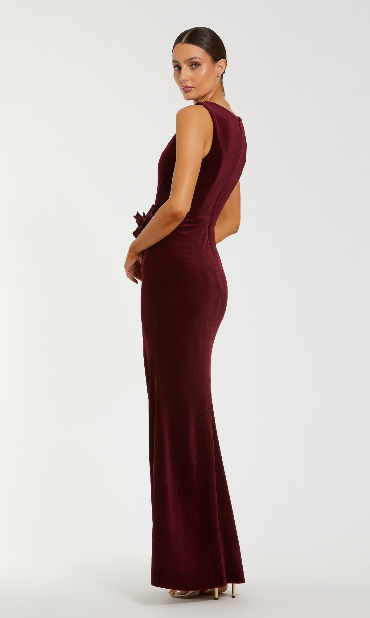 Woman modeling the back of a burgundy evening gown with a white background